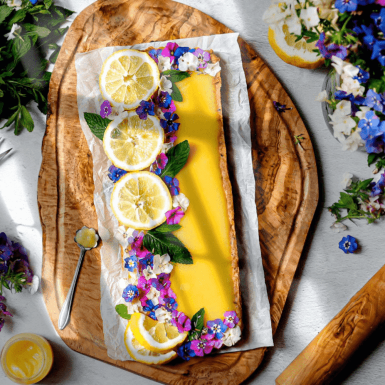 overhead shot of lemon curd shortbread styled with sliced lemons and dainty flowers on top