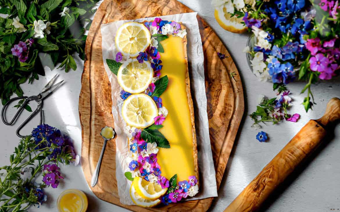 overhead shot of lemon curd shortbread styled with sliced lemons and dainty flowers on top