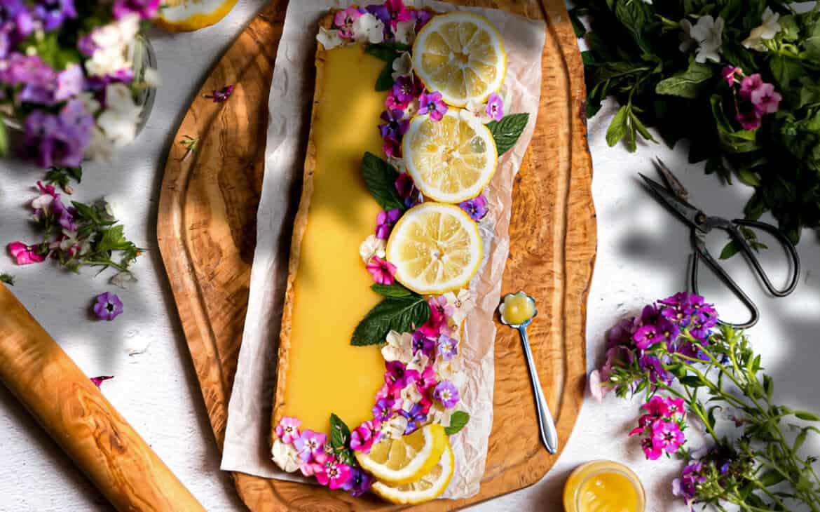 styled lemon curd shortbread tart with lemon slices and small dainty flowers