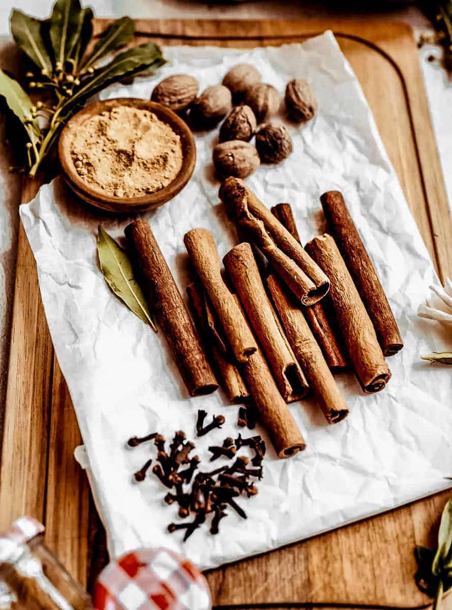 close up shot of whole spices needed for homemade pumpkin spice: cinnamon, nutmeg, clove and ginger