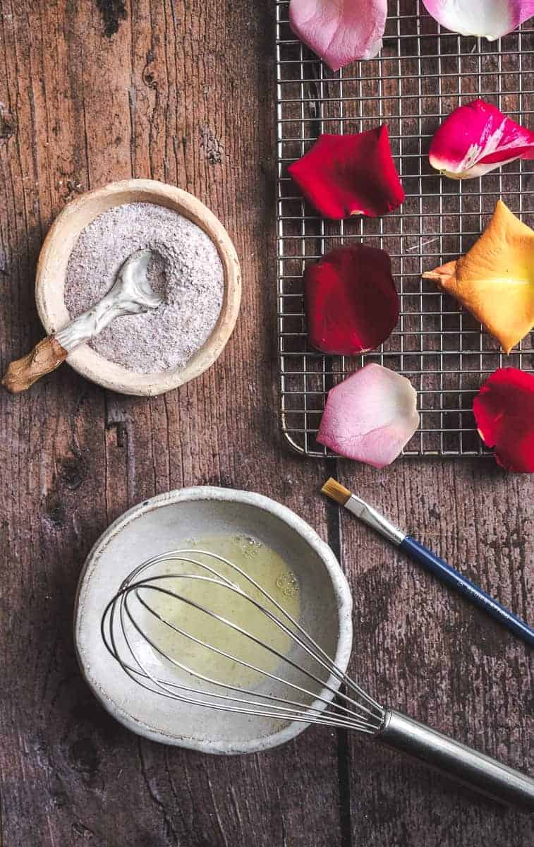 Pink roses petals in bowl with towels and pure water over white