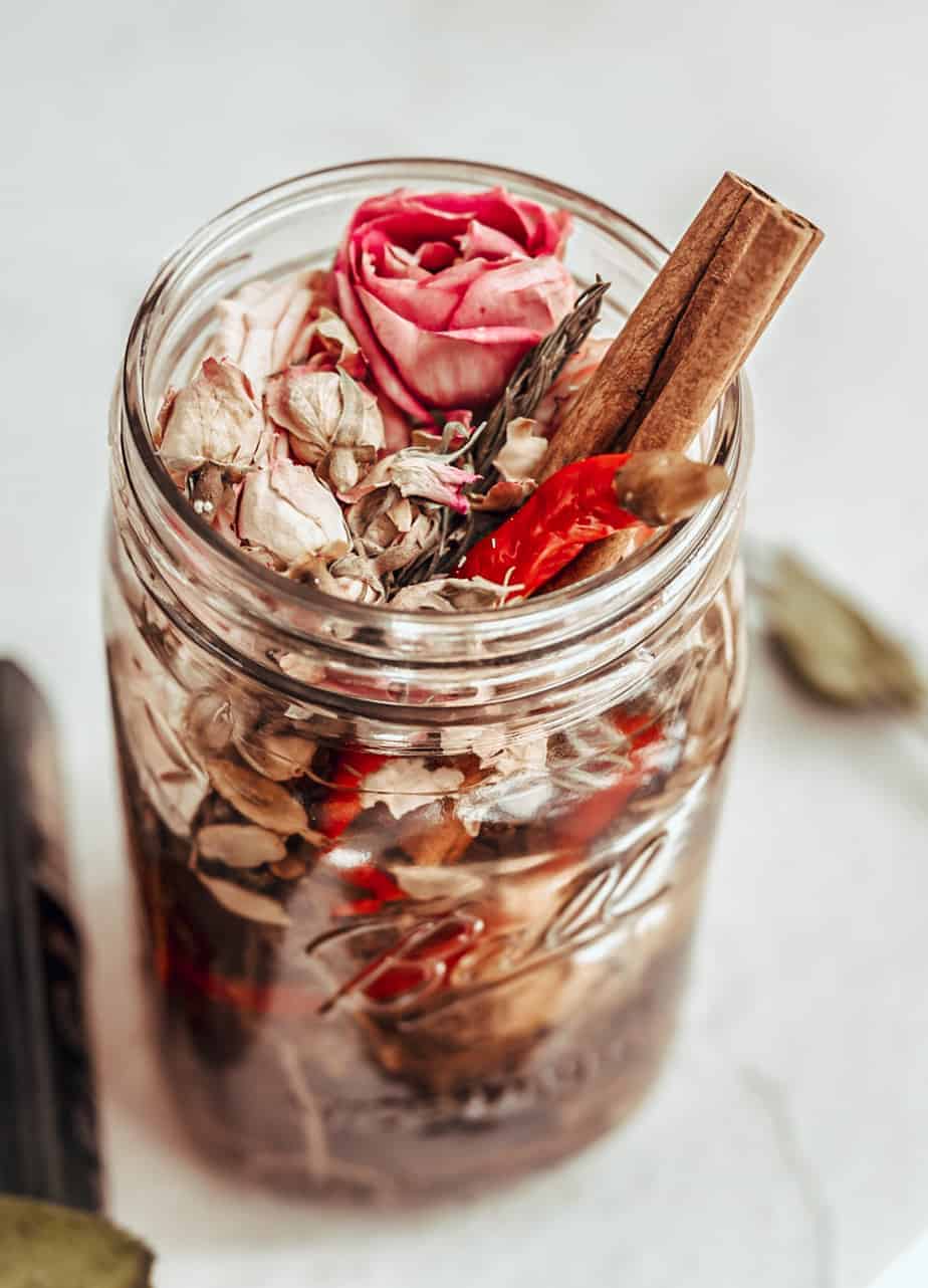overhead image of a jar filled with roses and cinnamon next to a rose and fairy tale book