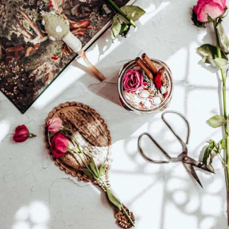 overhead image of a jar filled with roses and cinnamon next to a rose and fairy tale book
