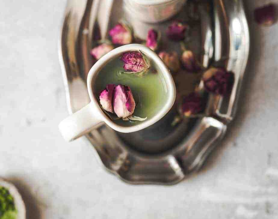 overhead shot of two mugs with beautiful green matcha and small rose bud