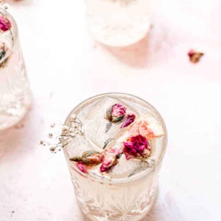overhead shot of a Paloma with rose petals and grapefruit in the glass on a pink background