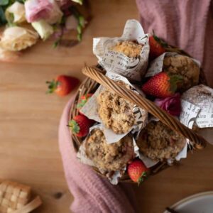 overhead image of strawberry crumble muffins in a basket with fresh strawberries