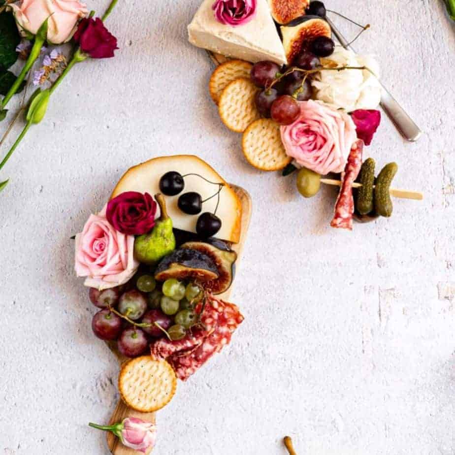 overhead shot of charcuterie board with grapes, cheese, and flowers