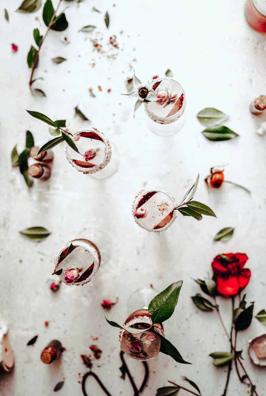 overhead shot of four elegant cocktail glasses with with rose simple syrup cocktail