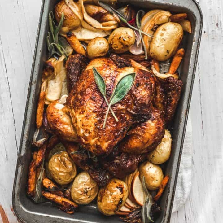 hero image overhead shot of one pan autumn roasted chicken dish with apples and sage in a small roasting pan