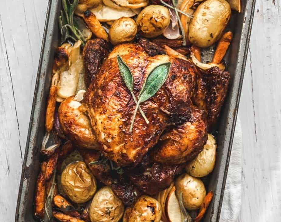 hero image overhead shot of one pan autumn roasted chicken dish with apples and sage in a small roasting pan