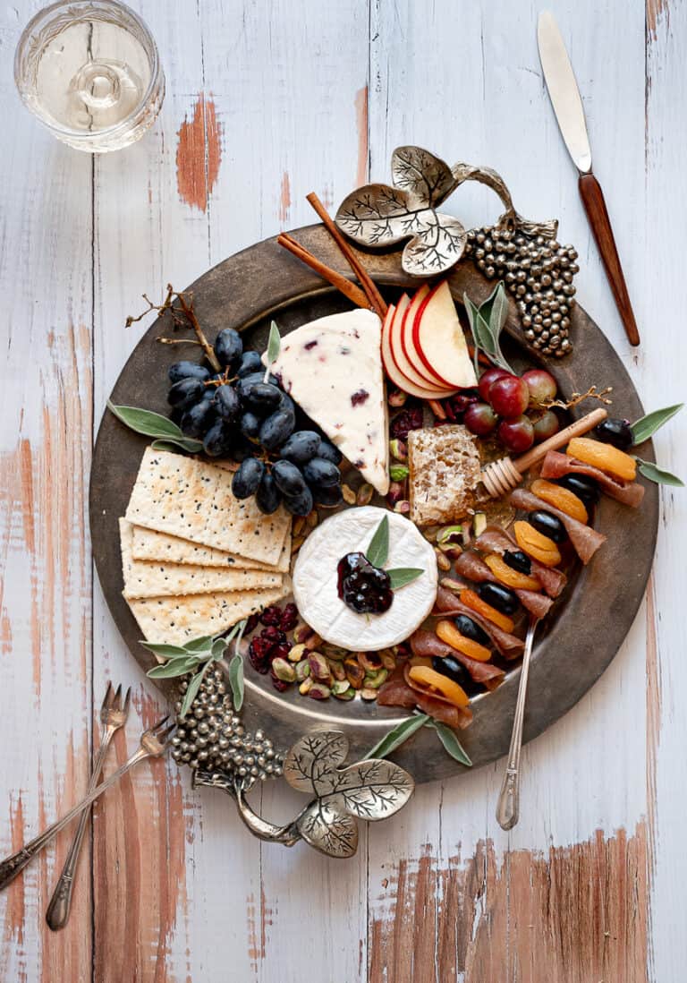 overhead shot of an autumn inspired charcuterie with cheese, crackers, grapes, meat and fruit
