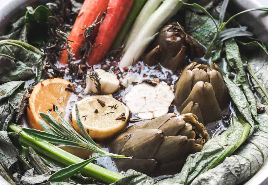 close up image of all of the ingredients in herbal bone broth in a large pot