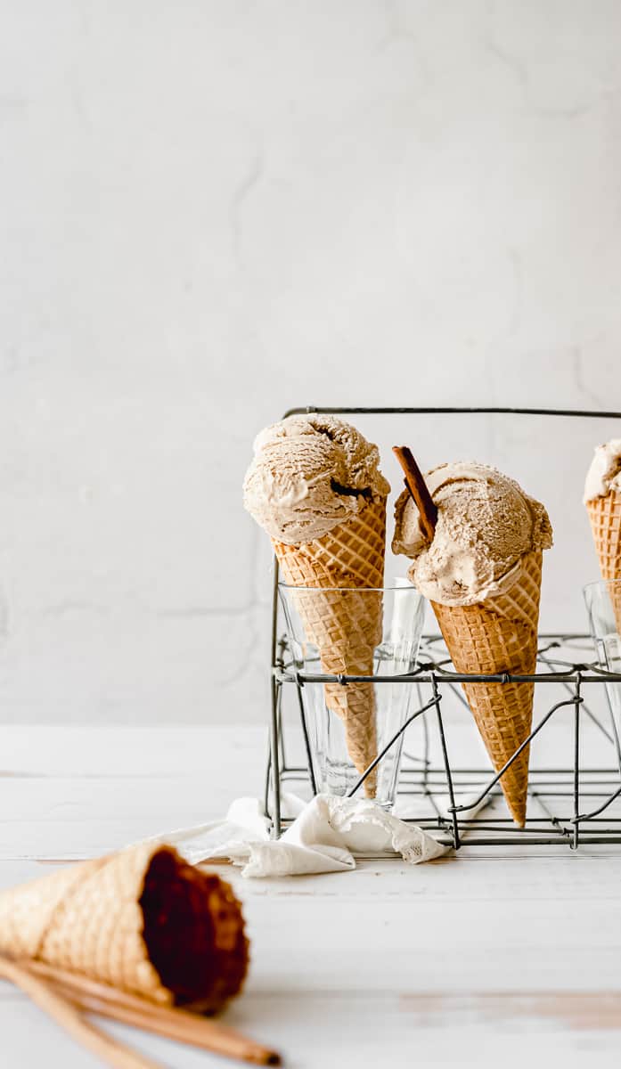 close up shot of two sugar cones in a vintage stand with scoops of homemade ice cream topped with a cinnamon stick