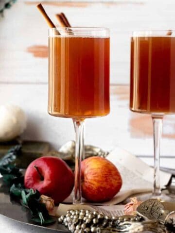 slow cooker apple cider in a tall glass with apples in the background
