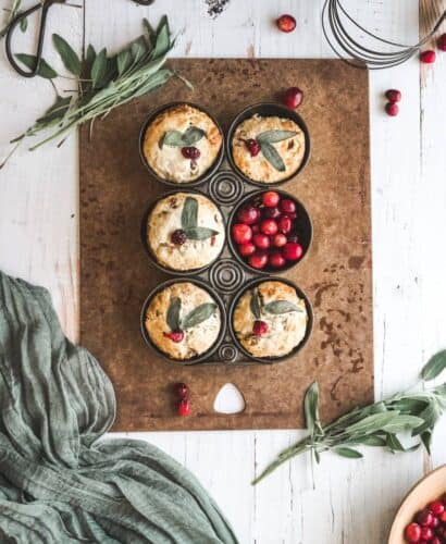 cover image of cranberry sage buttermilk biscuits - overhead shot of biscuits in a vintage in with sage leaves and fresh cranberry garnish