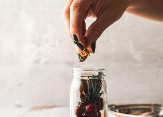woman's hands putting ingredients for winter infused honey into small jar