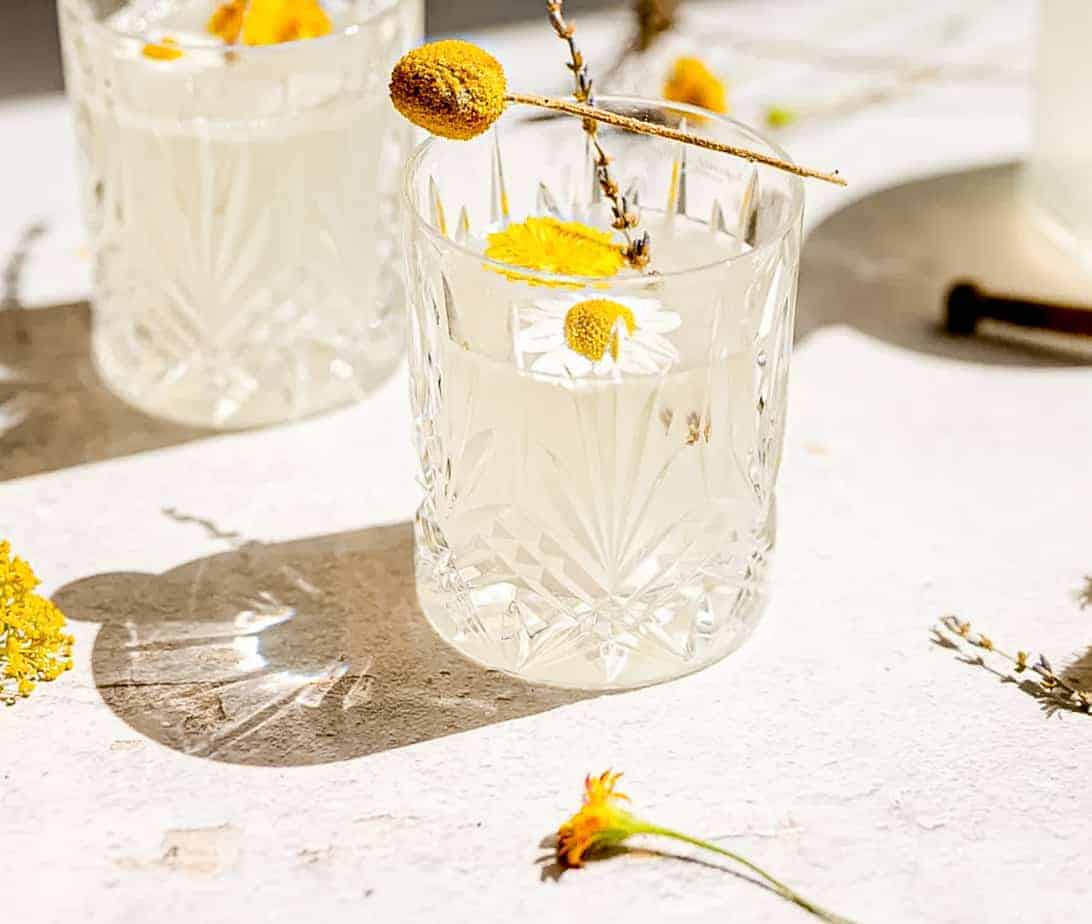 close up shot of dandelion lemonade with dandelion and chamomile flower floating on top