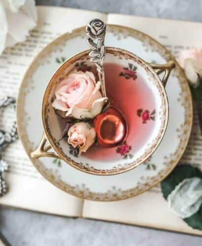 overhead shot of vintage rose and gold tea cup with pink rose tea with rose buds in the cup