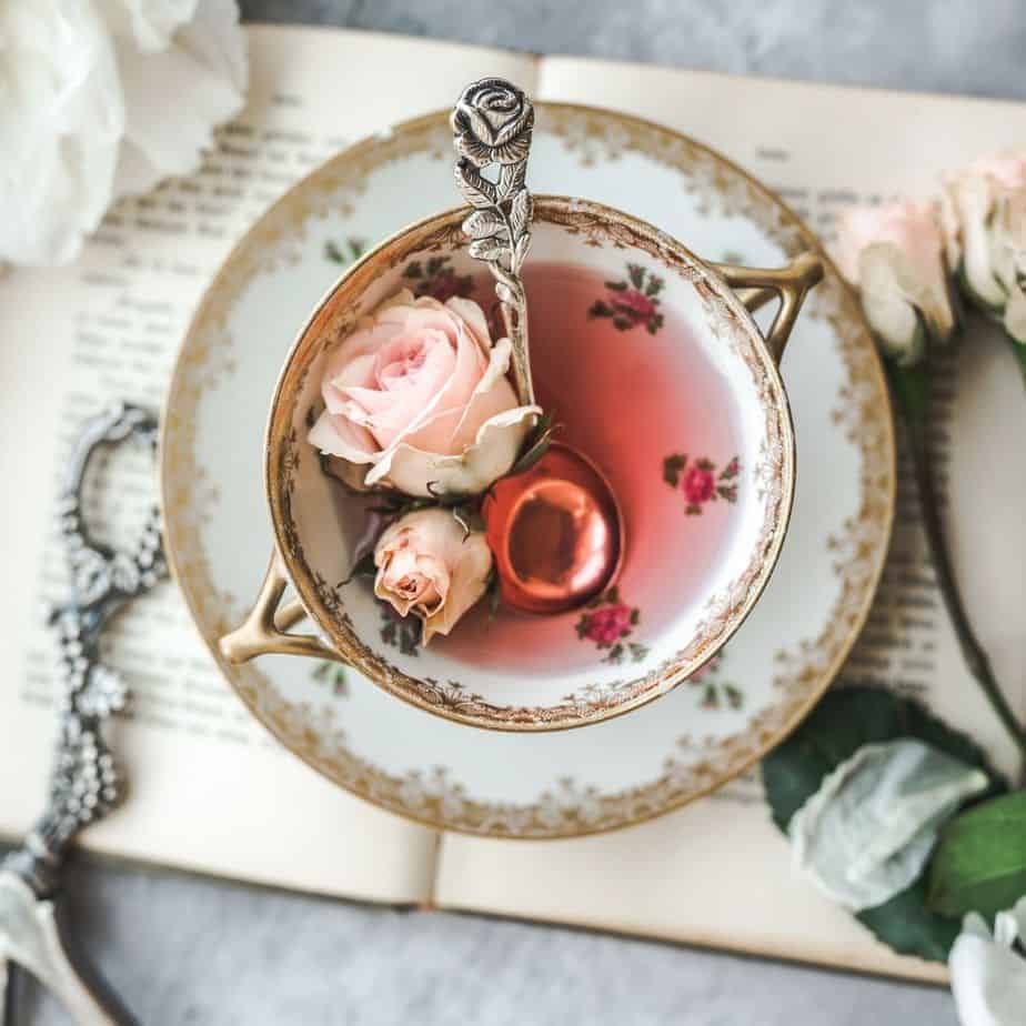 overhead shot of vintage rose and gold tea cup with pink rose tea with rose buds in the cup