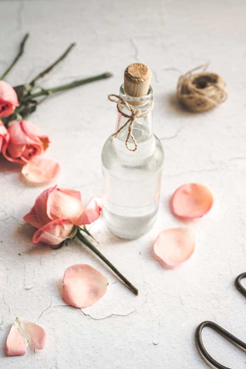 small glass jar of rose water with a cork screw