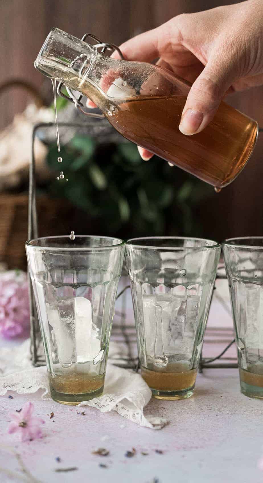 woman's hands pouring lavender honey simple syrup into a glass