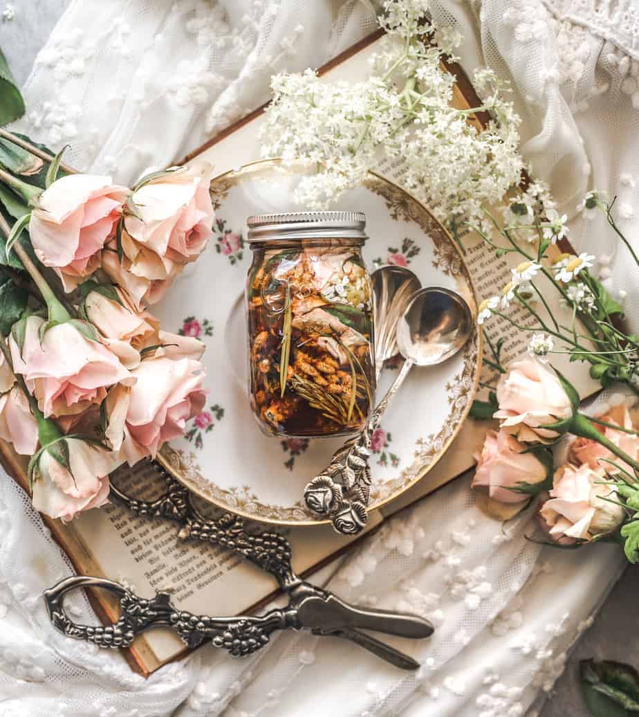 closed jar of floral infused honey on a plate surrounded by pink roses