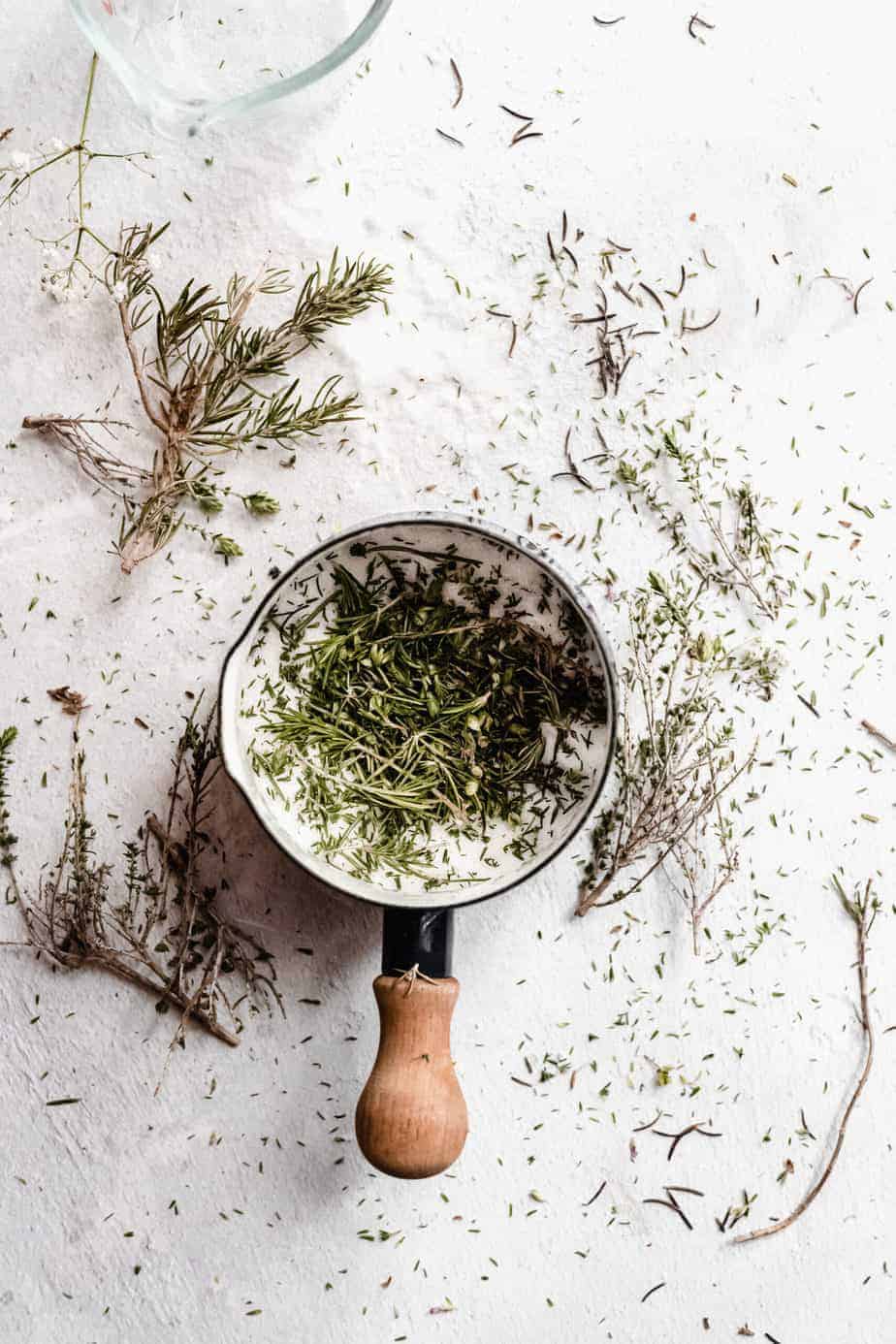 overhead shot of small sauce pan filled with rosemary and sugar for making rosemary simple syrup