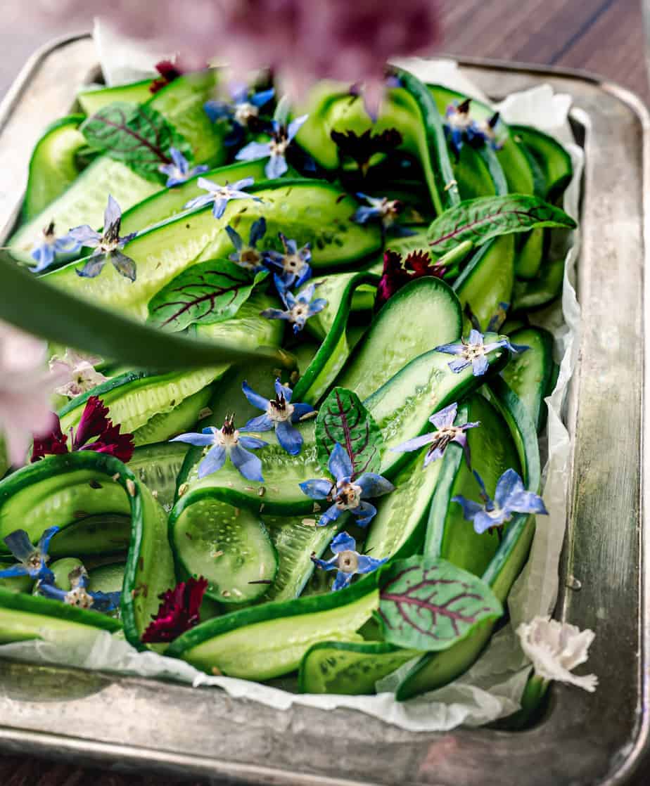 close up shot of sliced cucumbers and borage flowers