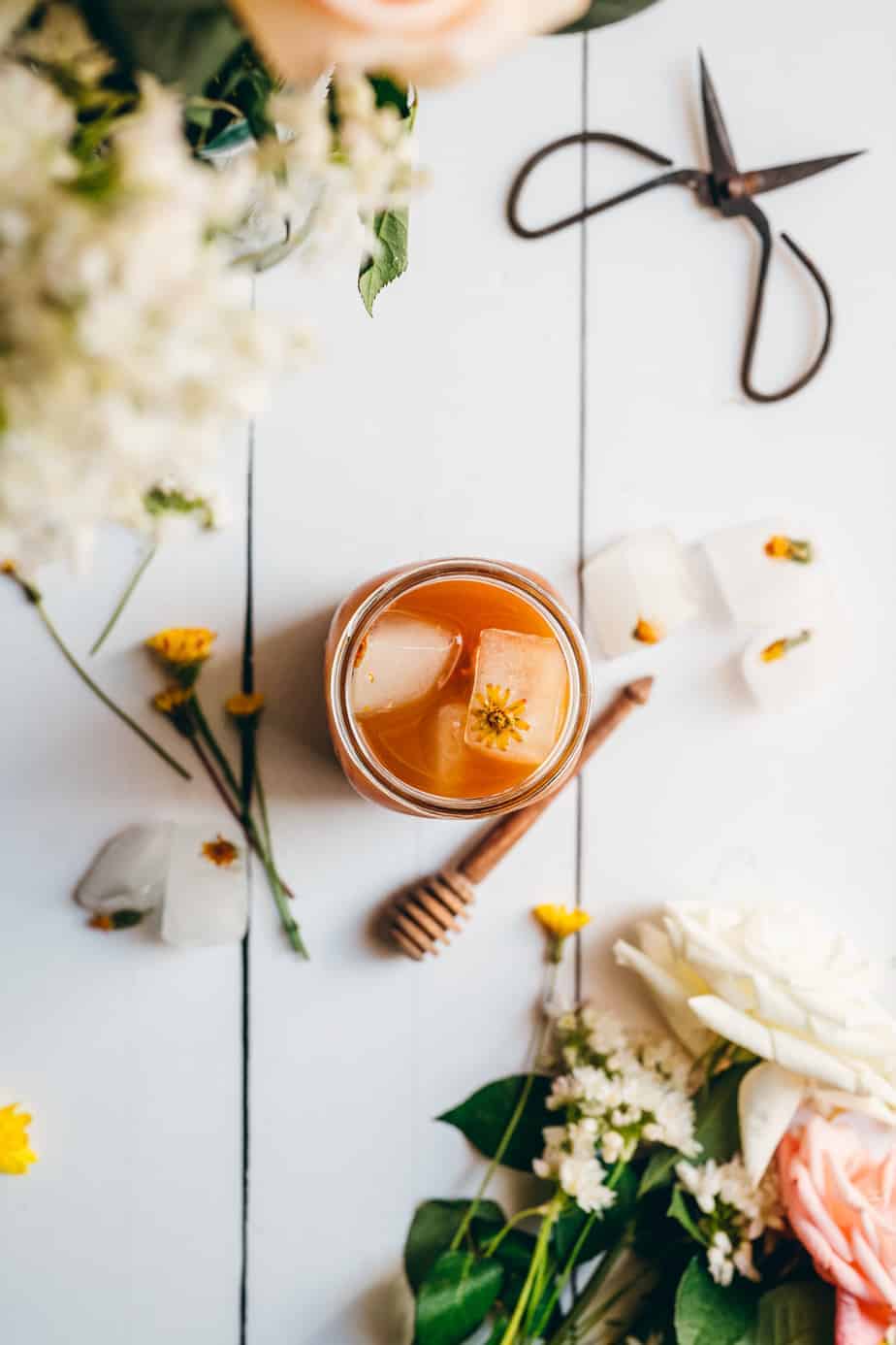 dandelion iced tea in a beautiful setting surrounded by flowers