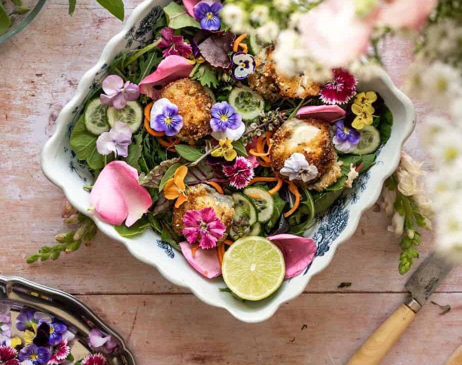 overhead image of bowl of greens filled with fresh organic flowers