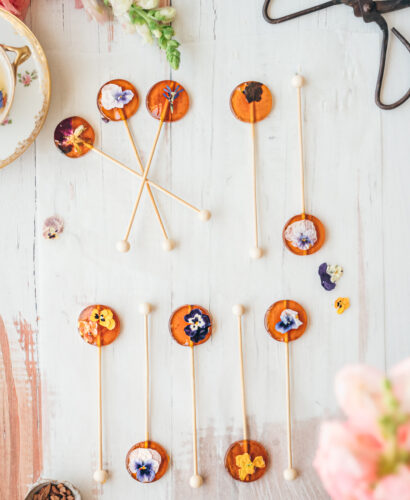 overhead image of honey spoons with pressed edible flowers on top