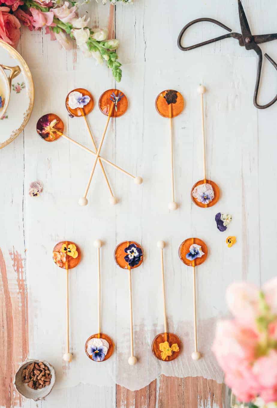 overhead image of honey spoons with pressed edible flowers on top