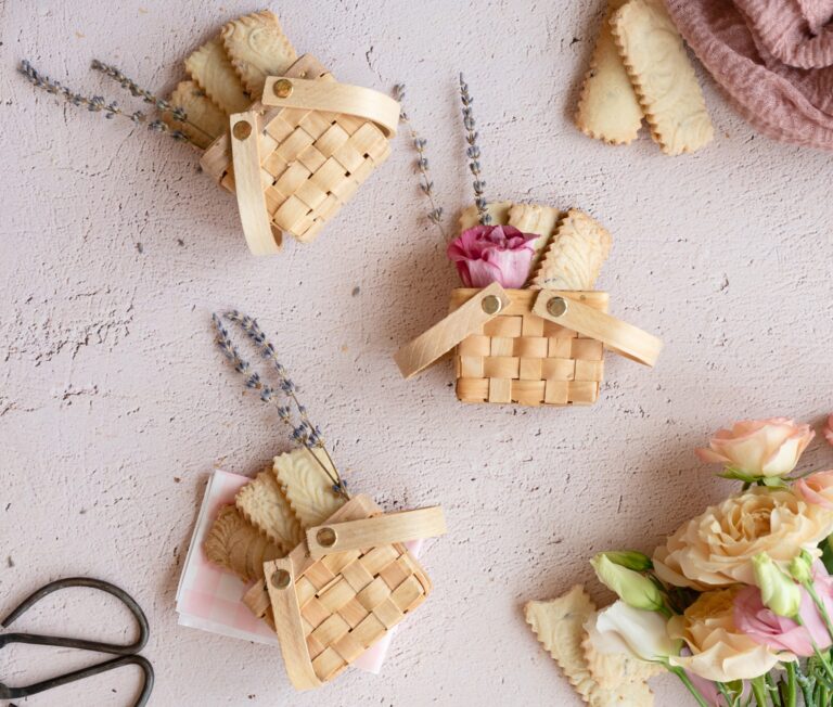 overhead image of miniature picnic baskets with lavender shortbread cookies and a dried lavennder sprig and pretty pink flower