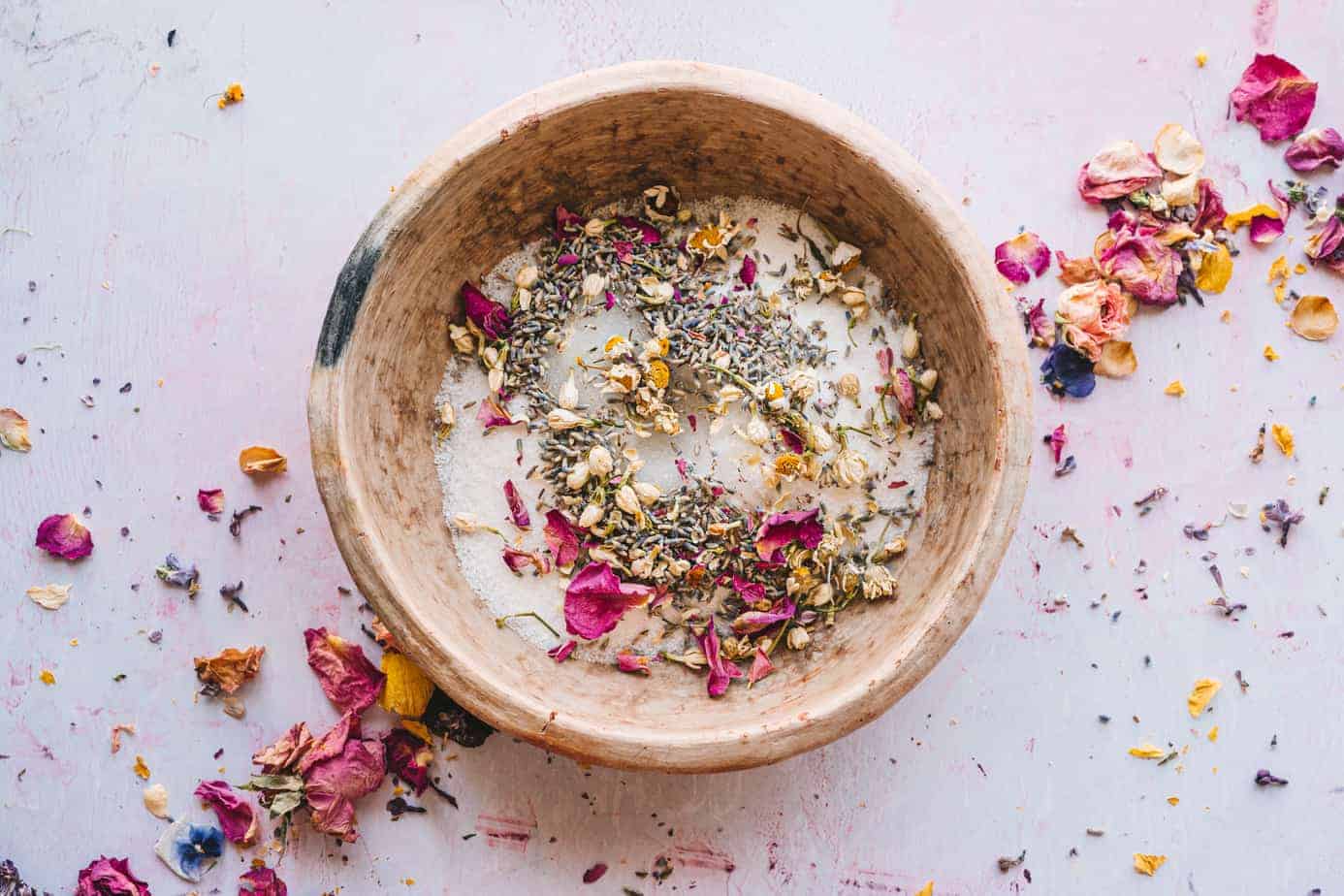 vintage pink bowl on lilac background filled with sugar and edible flowers