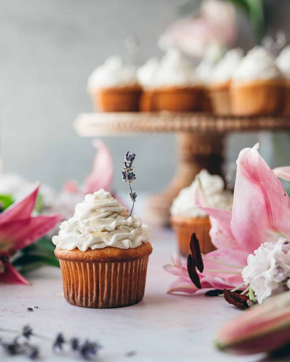 close up shot of a cupcake topped with lavender buttercream with a sprig of candied lavender garnishing it