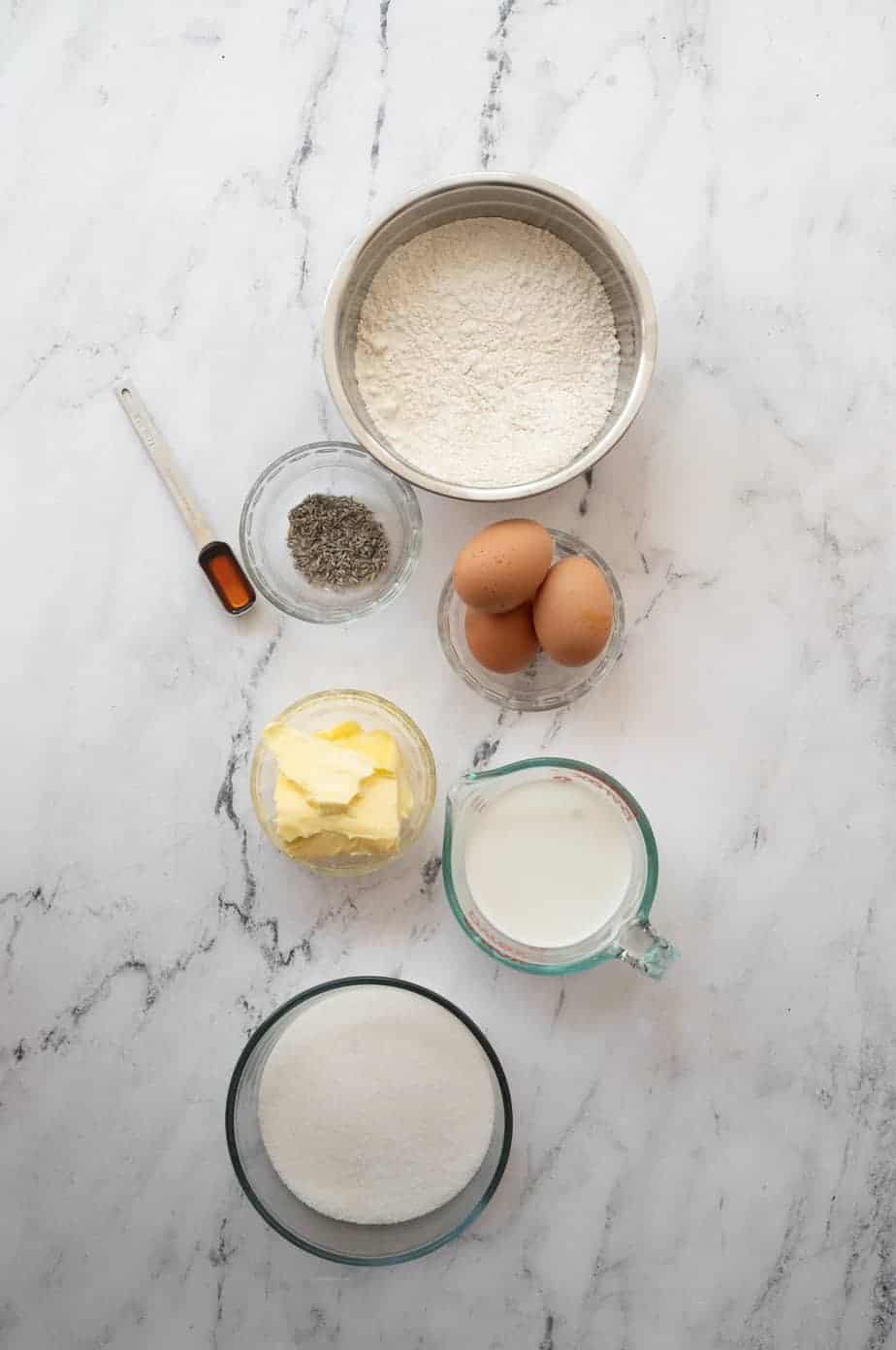 flatly of bowls of ingredients for lavender cake, bowl of flour, lavender, honey, butter, cream