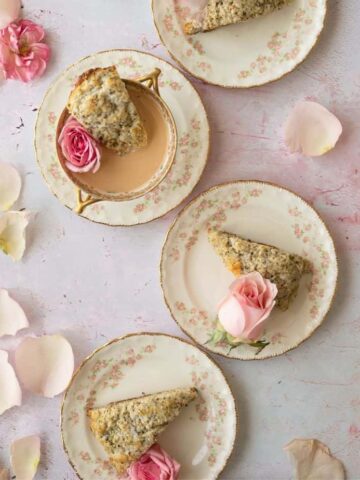 overhead image of three vintage dainty dishes with cup of Earl grey tea and earl grey scones with pink roses next to them