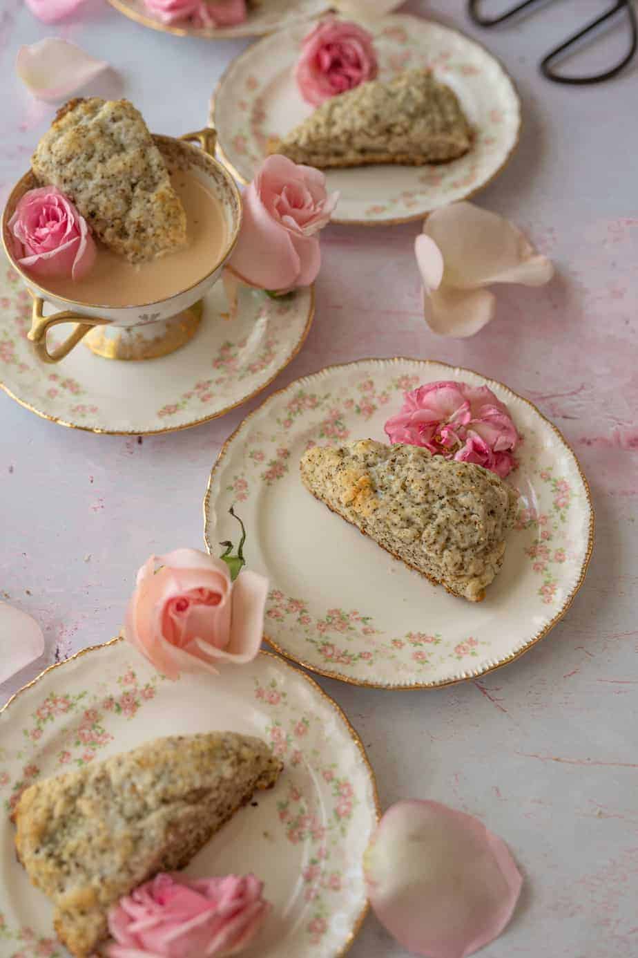 close up overhead image at 45 degree angle of plates of scones with pink roses on top