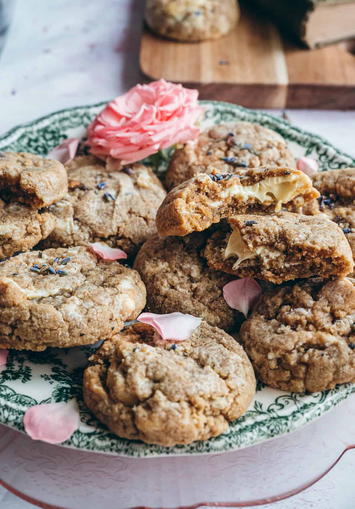 soft broken cookie showing gooey melted white chocolate one top of a plate with pink petals