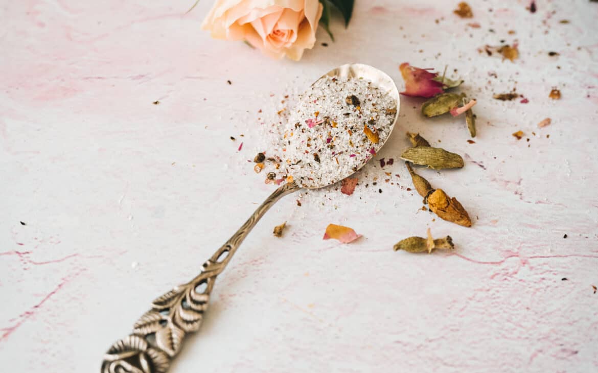 vintage spoon with silver rose at the end filled with granulated sugar and specks of rose petals