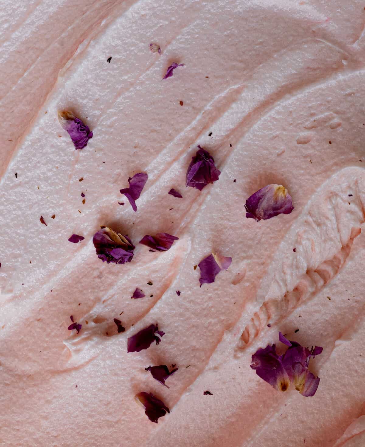 close up image of pink buttercream swirled with small dried pink roses in the center