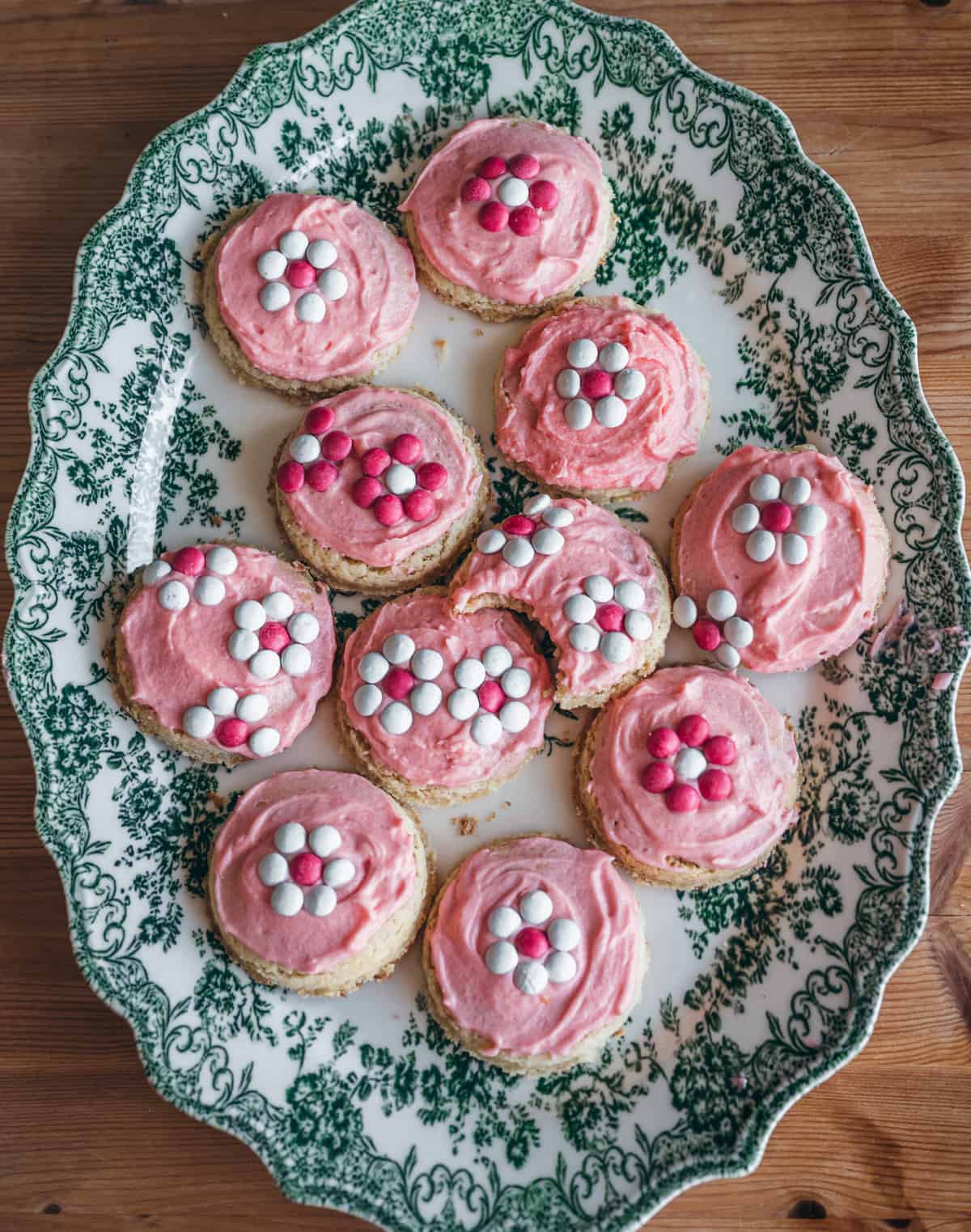 an arrangement of pink sugar cookies with daisy decorated m&ms
