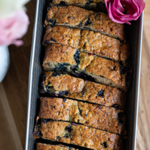 overhead shot of blueberry zucchini bread in baking loaf with pink flower on top