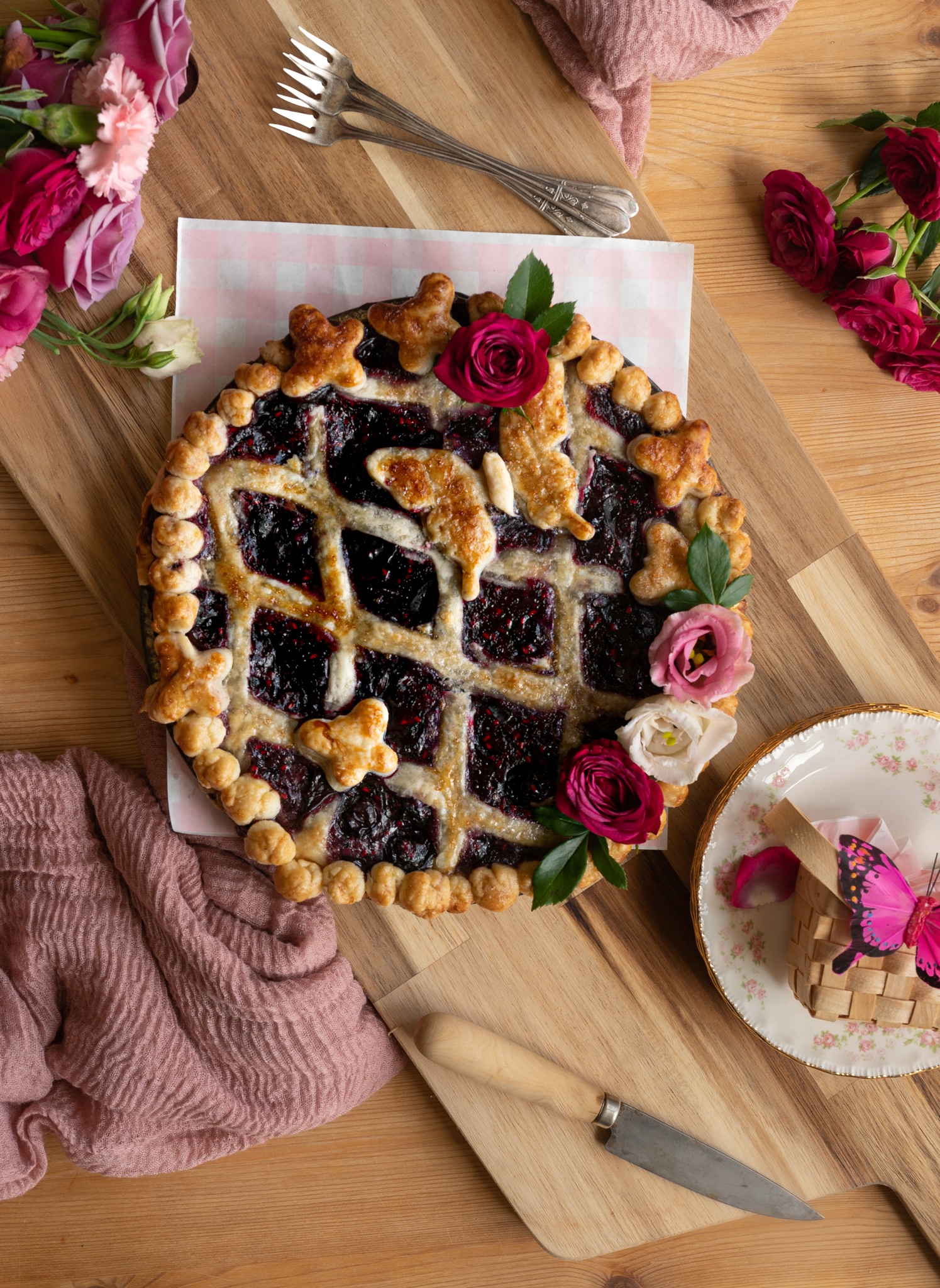 close up image of bright berry pie with gorgeous lattice crust with butterfly and pink flowers