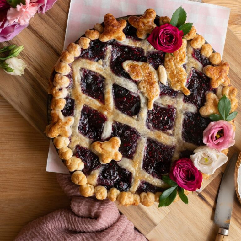 close up image of bright berry pie with gorgeous lattice crust with butterfly and pink flowers