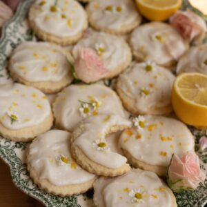 close up image of iced sugar cookies with chamomile flowers and zested lemon on top