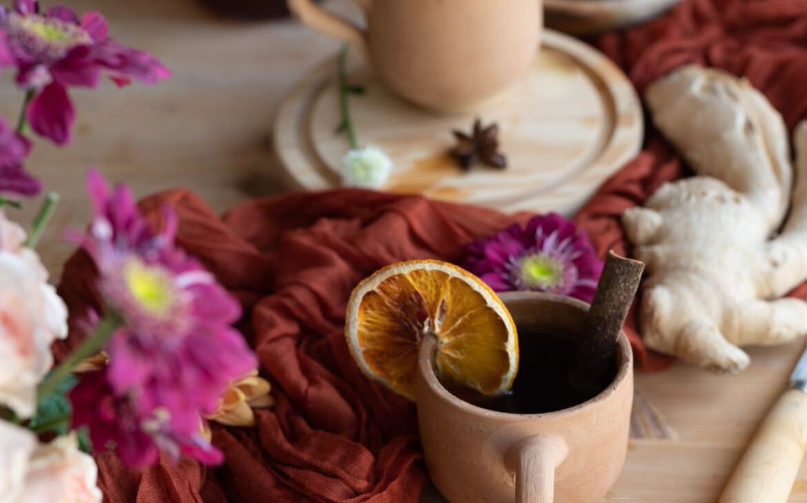close up image of terracotta cup with orange slice and big piece of ginger showing healing herbal spiced cider