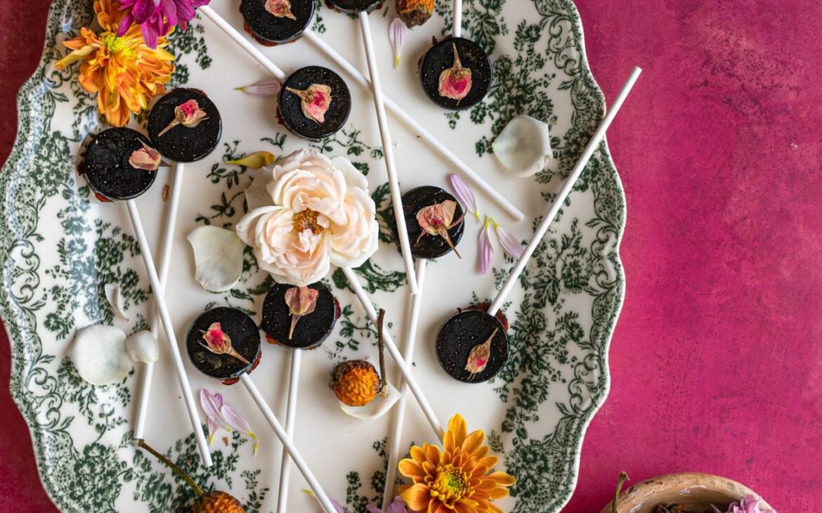 vibrant pink backdrop with vintage plate with rose hip and elderberry lollipops with dried rose hips
