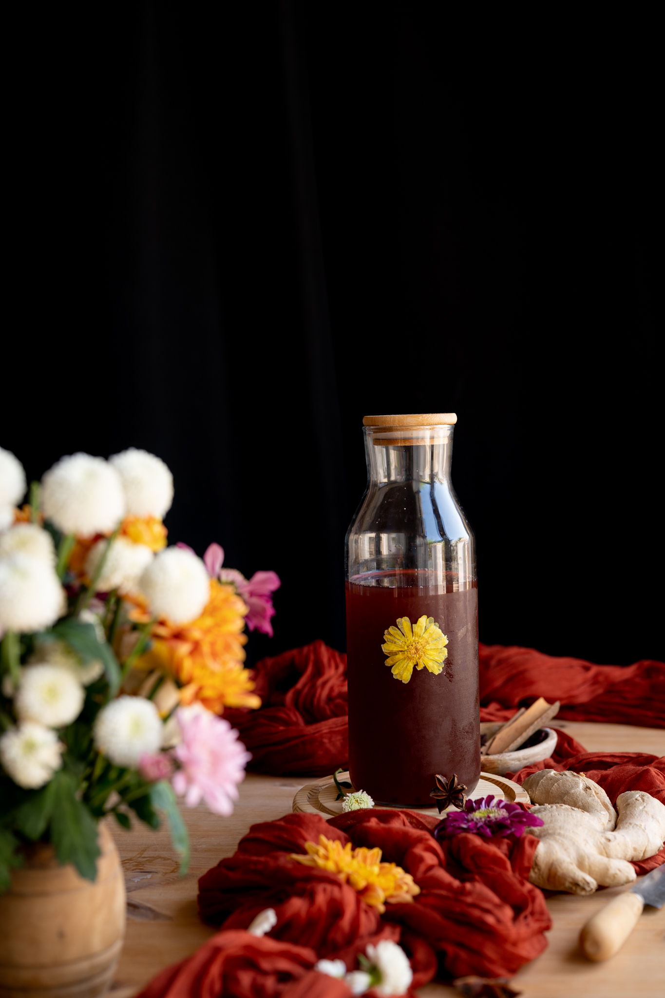close up image of stovetop herbal spiced cider next to autumn bouquet of flowers