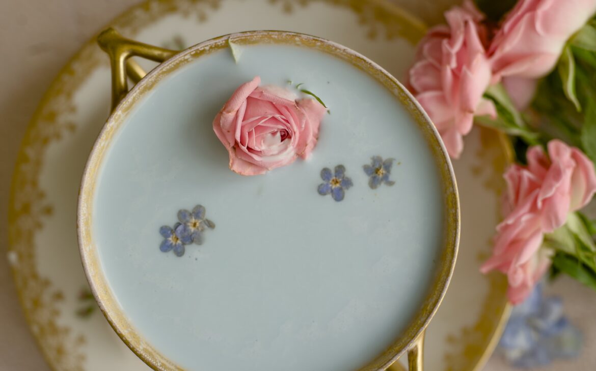 overhead image of blue moon milk tea with forget me not flowers and a rose bud